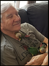 Man smiling with eyes closed and three birds on his chest